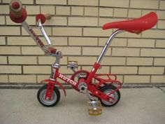 a red tricycle is parked in front of a brick wall with a bicycle handlebar