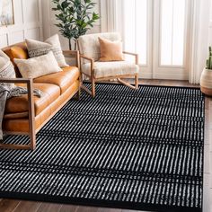 a black and white rug in a living room with two chairs, a couch and a potted plant