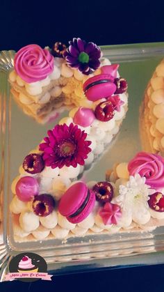 there is a number made out of cookies and flowers on the cake platter with pink frosting