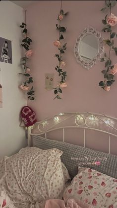 a bedroom with pink walls and flowers hanging on the wall