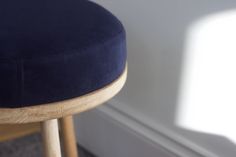 a close up of a stool with a blue cushion on the back and wood legs