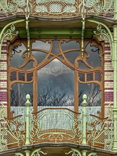 an ornate balcony with wrought iron railings and wooden windows, in front of a red brick building