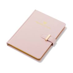 a pink notebook with a gold ring on the front and side, sitting on a white surface