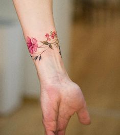 a woman's hand with a flower tattoo on her left wrist and the other arm