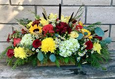 a wooden box filled with lots of flowers and greenery next to a brick wall