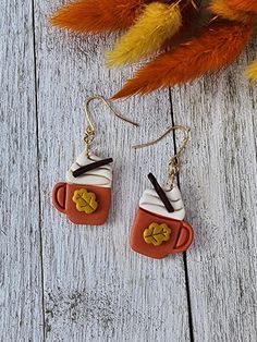 a pair of coffee mugs with hearts on them are hanging from gold ear wires