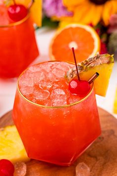 a close up of a drink on a table with fruit and flowers in the background