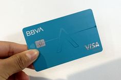 a hand holding a blue visa card with the word bbva on it's front