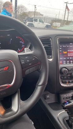 the interior of a car with an electronic display and steering wheel controls in front of it