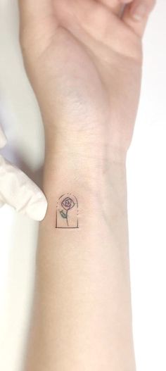 a small tattoo on the wrist of a woman's left arm, with a flower in it