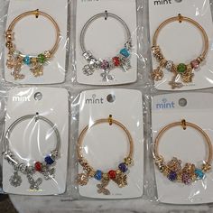 six pairs of bracelets with charms on them for sale in a store display case