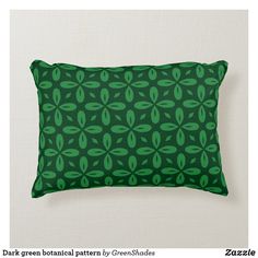 a green pillow with leaves on it is sitting against a white wall and has the words dark green botanical pattern by greensdales