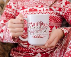 a woman is holding a coffee mug in her hands while sitting on a couch with the words north pole charlotte printed on it