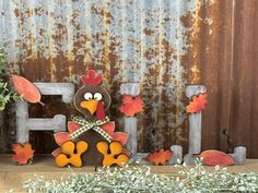 a turkey sitting on top of a wooden bench next to fall leaves and a potted plant