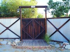 a wooden gate with two gates on each side and rocks in the foreground behind it