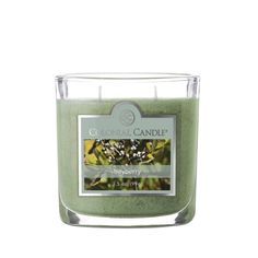 a candle that is green with white flowers on the top and bottom, in front of a