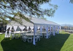 a large tent set up with white tables and chairs