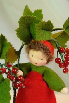 a small doll with red berries and green leaves