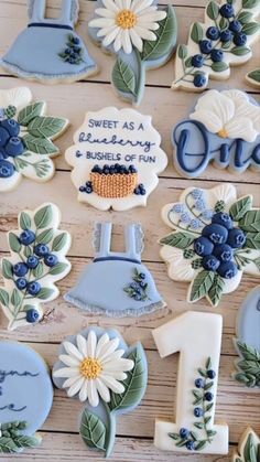 decorated cookies with blue and white flowers on wooden table next to number one cookie cutters