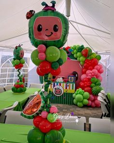 some very pretty balloons in the shape of fruits and vegetables on a table under a tent