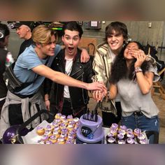 a group of people standing around a table with cupcakes