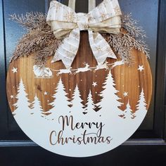 a merry christmas door hanger with a bow on it's front door, decorated with pine trees and snowflakes