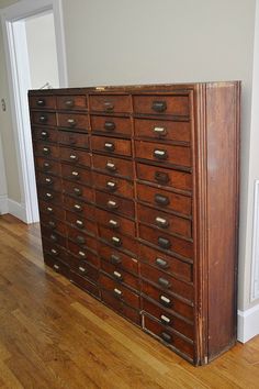 an old wooden filing cabinet sitting on top of a hard wood floor