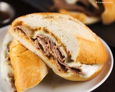 a sandwich with meat and cheese on a plate next to some dipping sauce in a bowl