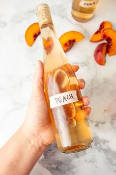 a person holding a bottle with peaches in it and the label says peach on it