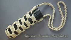 a crocheted bag with a black and white handle is on the ground next to a chain