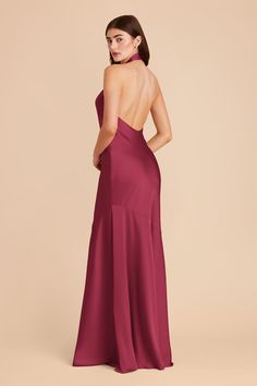 the back of a woman in a long red dress with one shoulder and open back