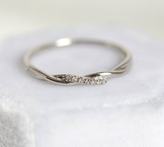 a white gold ring with three diamonds on top of a cloth covered napkin, close up