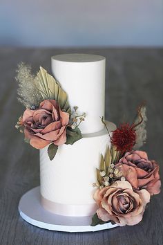 a three tiered white wedding cake with flowers on top