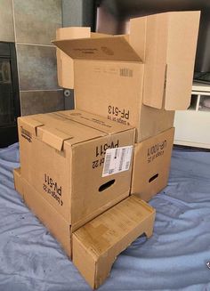 several boxes stacked on top of each other on a bed in a room with blue sheets