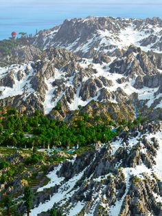 an aerial view of a mountain range with snow on the mountains and trees in the foreground