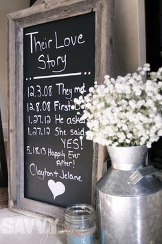 there is a chalkboard sign on the wall next to a vase with baby's breath in it