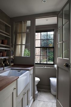 an open door leading to a bathroom with a sink, toilet and window in it