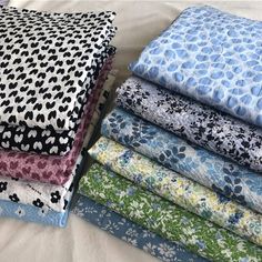 a pile of fabric sitting on top of a bed next to each other in different colors