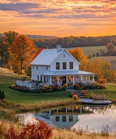 a large white house sitting on top of a lush green field next to a lake