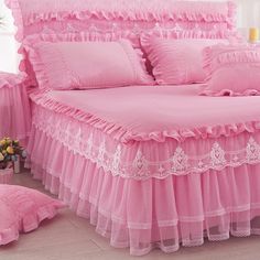 a pink bed with ruffled bedspread and pillows