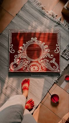 a woman's feet with red and white patterned rug on the floor in front of her