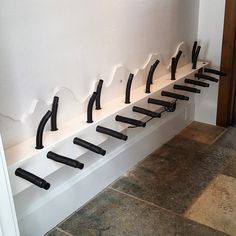 a row of black handles on a white wall in front of a set of doors