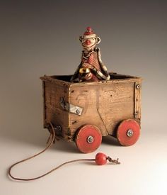 an old wooden toy train with a monkey sitting on it's top and two red wheels