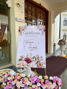 a welcome sign sitting on top of a table filled with flowers