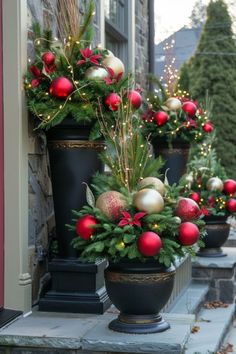 christmas decorations are lined up on the front steps in black urns with red and gold ornaments