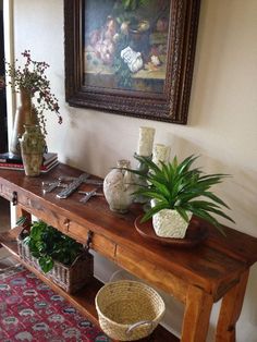 a wooden table topped with potted plants next to a painting on the wall above it