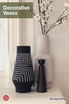 two black and white vases sitting on top of a table