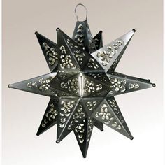 a metal star ornament hanging on a white wall with silver filigreets