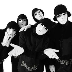 five masked men pointing at the camera with their hands in each other's pockets