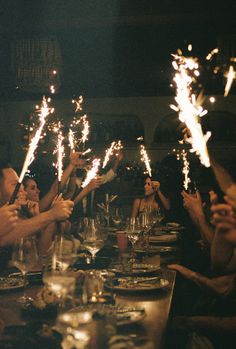 a group of people sitting around a table with sparklers in their hands